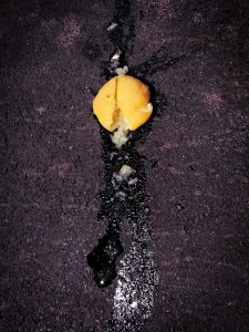 A flattened lemon on pavement